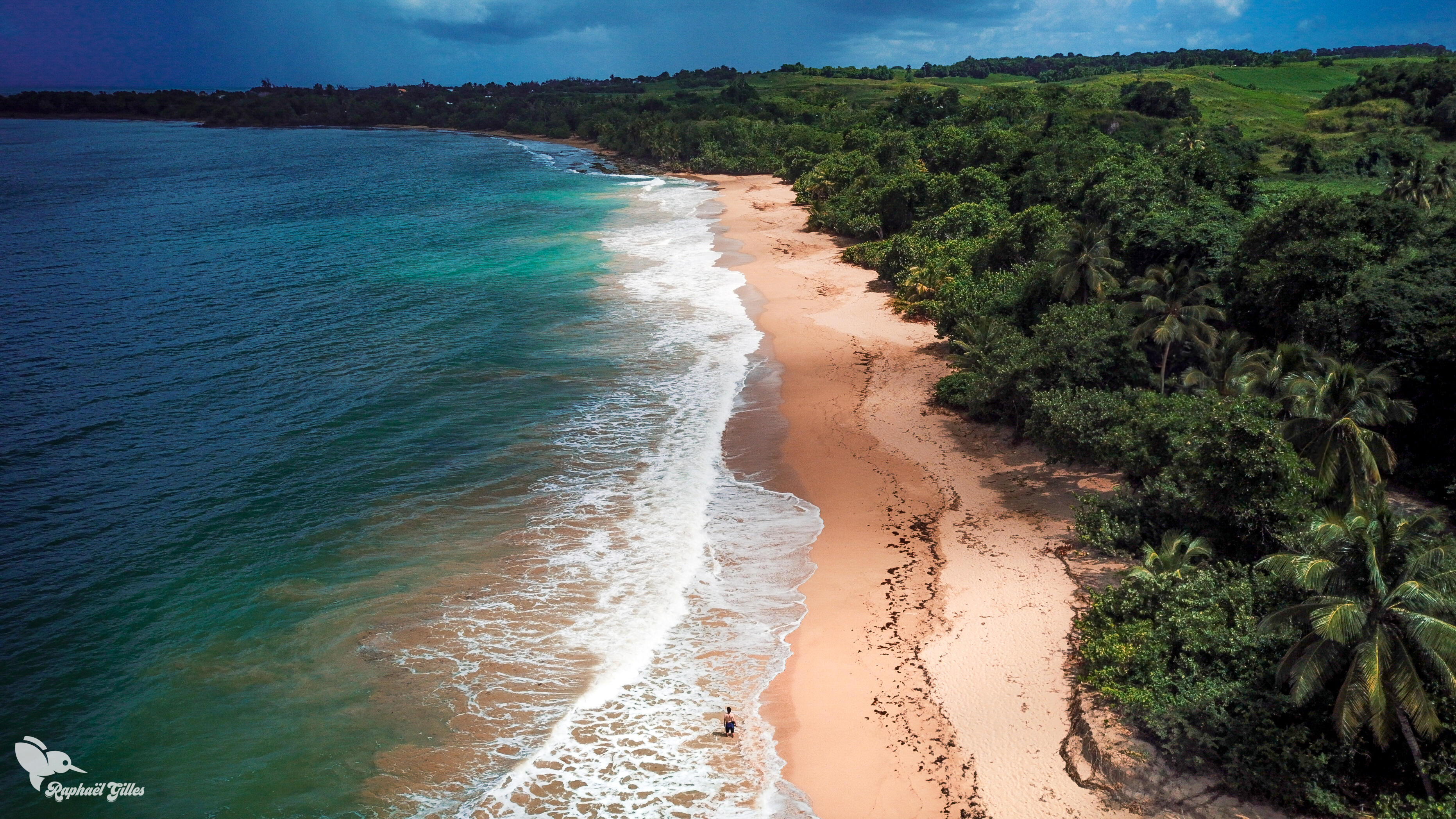 Photo au drone. Une grande plage de sable blanc. Un homme les pieds dans la mer.