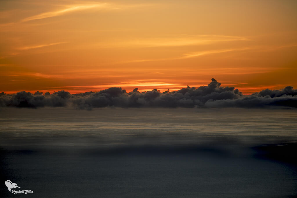 Un coucher de soleil.
Des nuages se reflètent dans la mer.