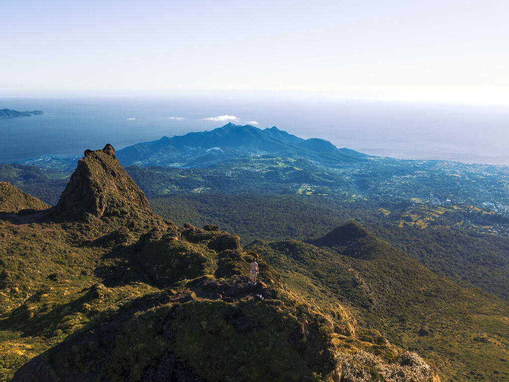 Photo prise au drone.
Un homme au sommet d’un volcan. Au loin un immense paysage devant lui.
