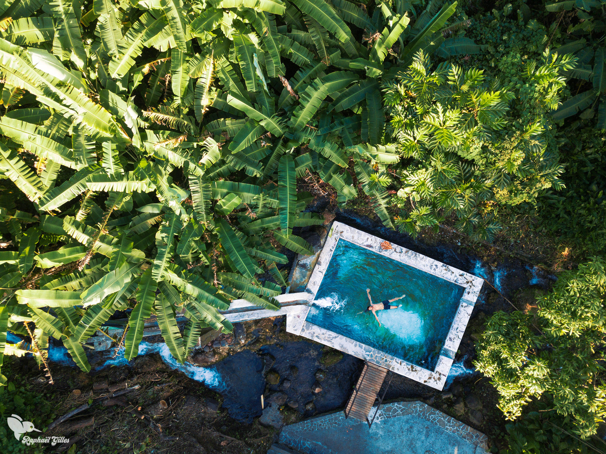 Photo prise au drone. Un homme se baigne dans un bassin au milieu de la forêt tropicale.