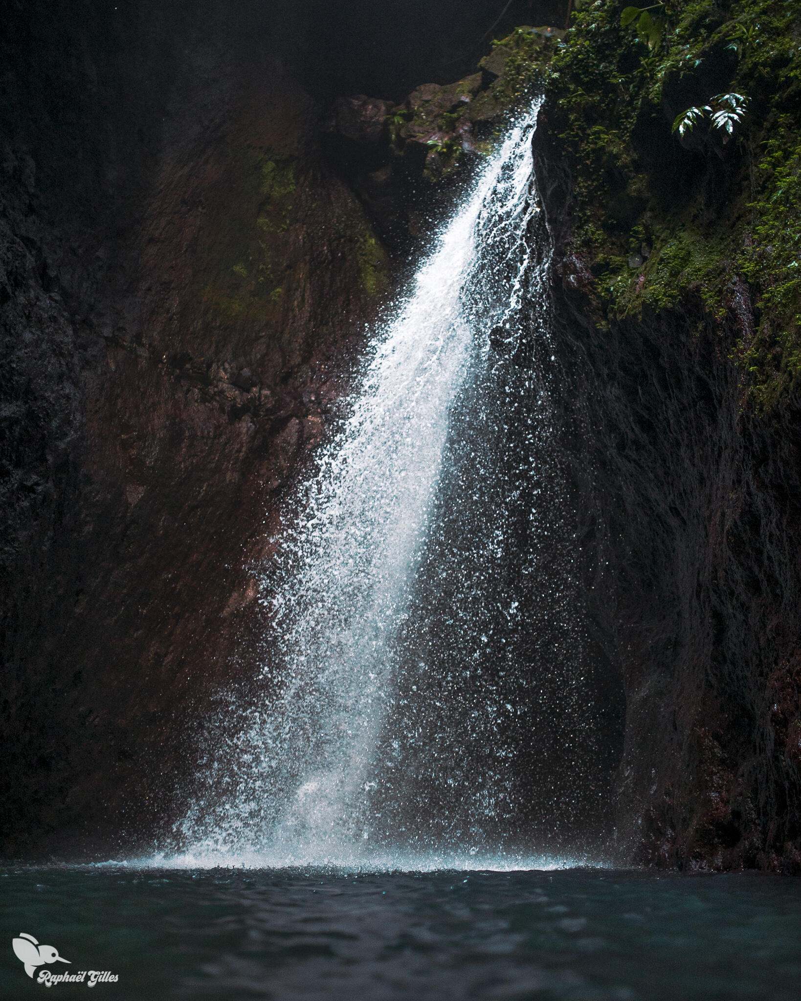 Une cascade plonge dans un bassin bleu.