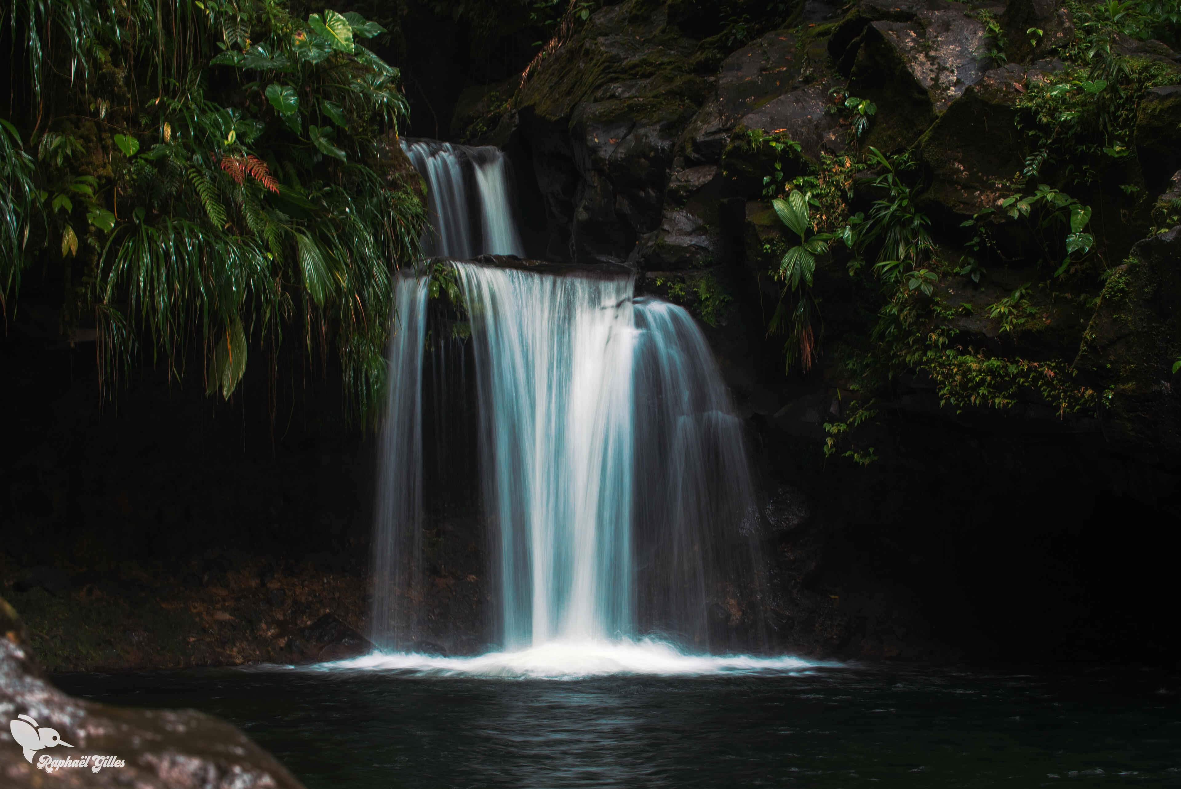 Photo prise en pose longue.
Une cascade se jette dans un bassin.