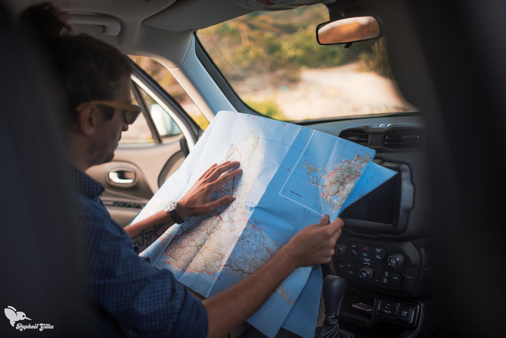 Une homme dans une voiture regarde une carte de la Guadeloupe.