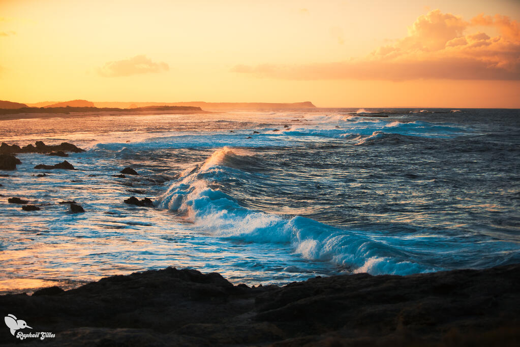 L'Océan Atlantique frappe la côte ouest de la Guadeloupe avec d'immenses vagues, sous un coucher de soleil.